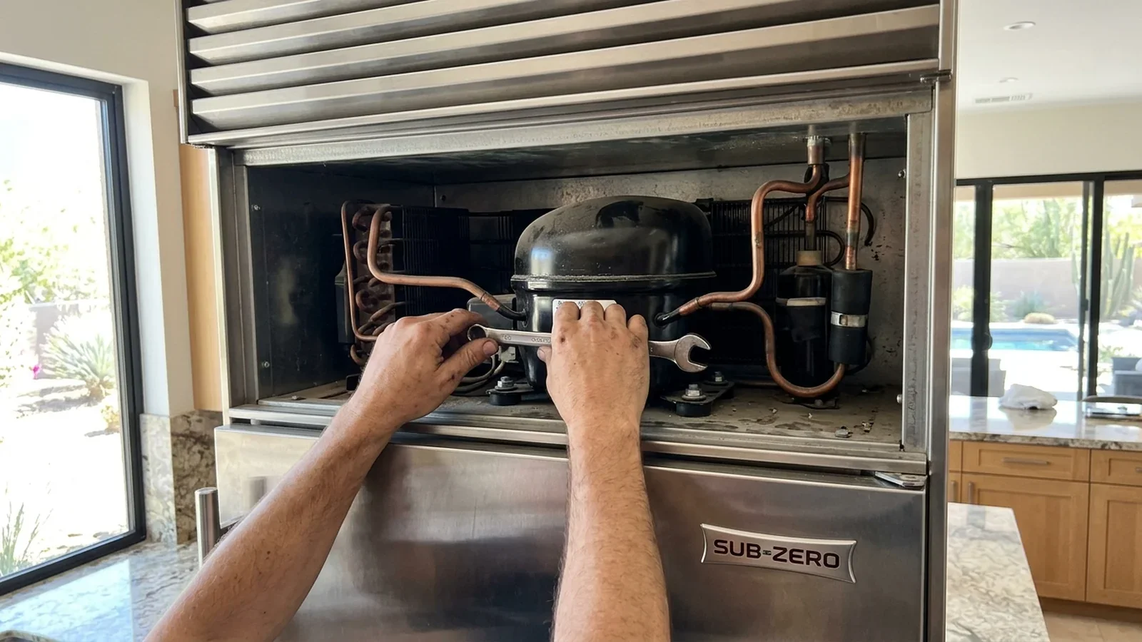 Technician working on the compressor in the top compartment of a Sub-Zero built-in refrigerator